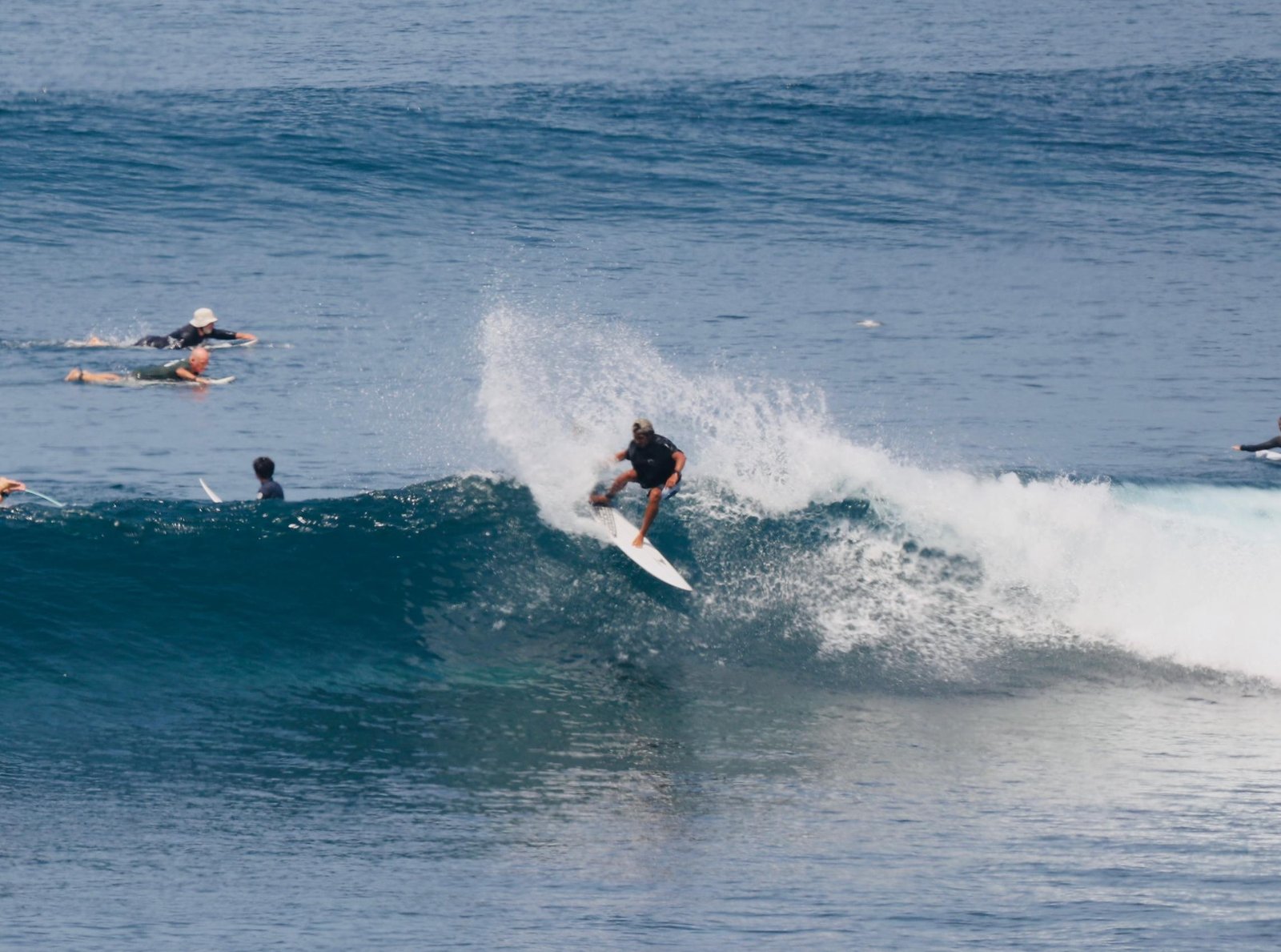 Surfer executing a sharp turn generating ocean spray at Padang Padang beach
